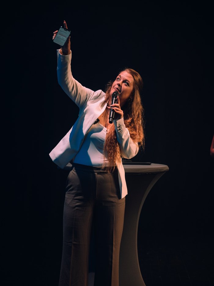 Lena zeigt auf der Bühne ihr Handy